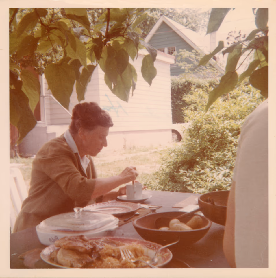 Tatyana Grosman sitting at the lunch table in the front yard of Skidmore Place. Image courtesy of Universal Limited Art Editions.