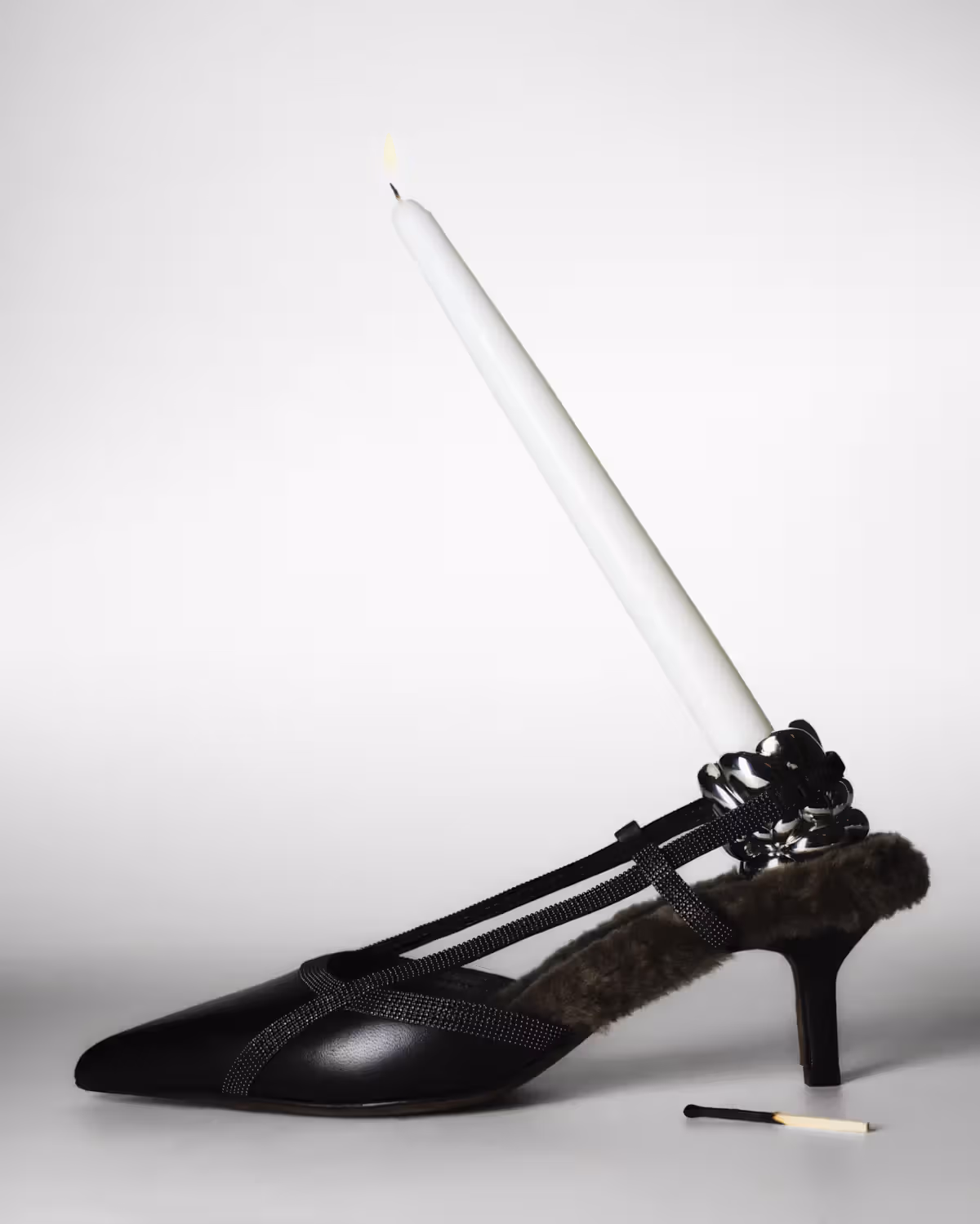 Shoe by BRUNELLO CUCINELLI and candle holder by CHRISTOFLE.